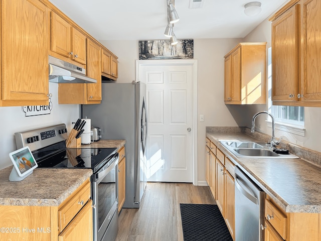 kitchen featuring appliances with stainless steel finishes, sink, track lighting, and light hardwood / wood-style floors