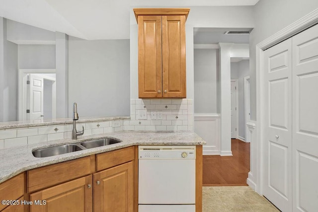 kitchen with sink, light stone countertops, white dishwasher, and decorative backsplash