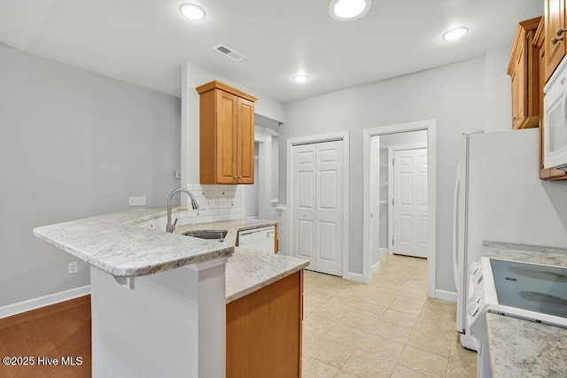 kitchen with kitchen peninsula, sink, tasteful backsplash, stove, and a breakfast bar