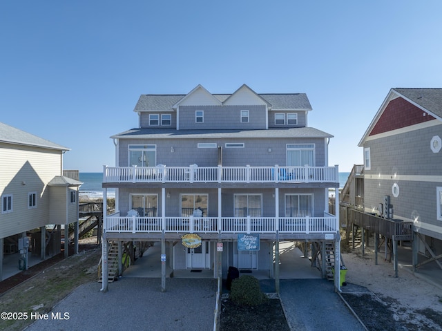 view of front facade with a water view, a balcony, a carport, and covered porch