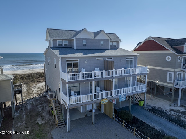 exterior space featuring a carport, a water view, central AC unit, a beach view, and a balcony