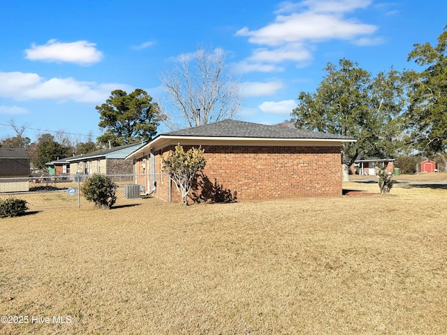 view of side of property with central AC and a lawn