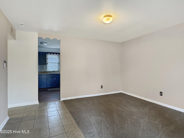 spare room with sink, dark tile patterned flooring, and a textured ceiling