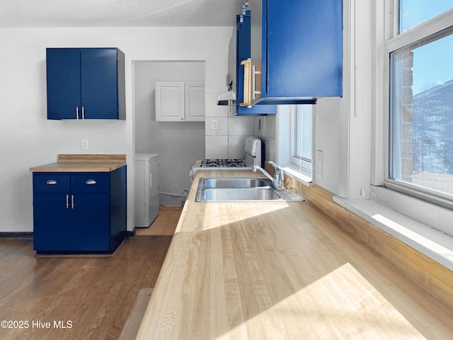 kitchen featuring dark hardwood / wood-style flooring, sink, washer and clothes dryer, and blue cabinets