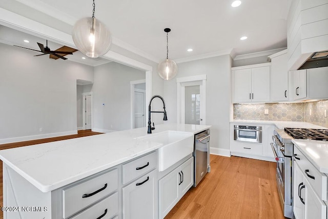 kitchen featuring sink, hanging light fixtures, appliances with stainless steel finishes, an island with sink, and white cabinets