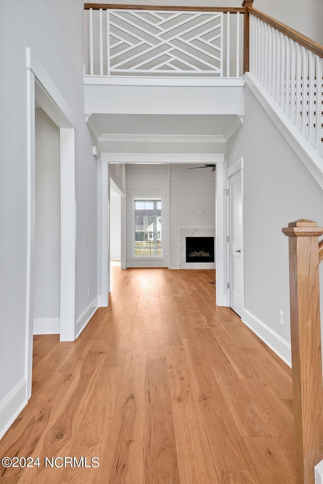 unfurnished living room with light hardwood / wood-style floors, a towering ceiling, and a fireplace