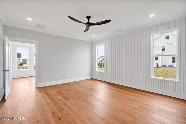 spare room with light wood-type flooring, a wealth of natural light, and crown molding