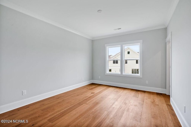 empty room with ornamental molding and light hardwood / wood-style floors