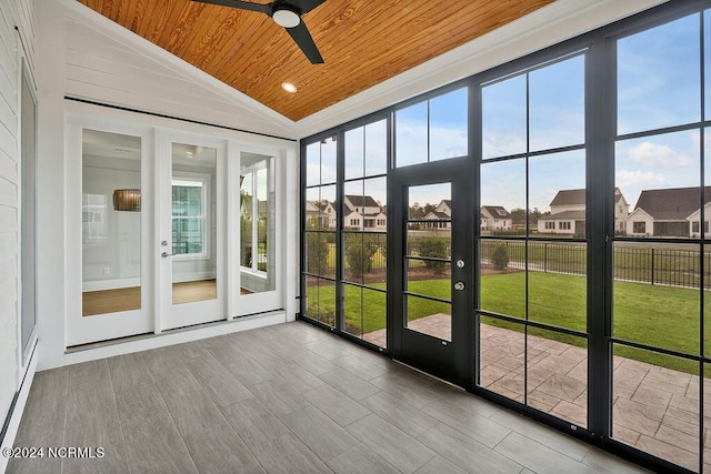 unfurnished sunroom featuring vaulted ceiling, ceiling fan, wood ceiling, and plenty of natural light