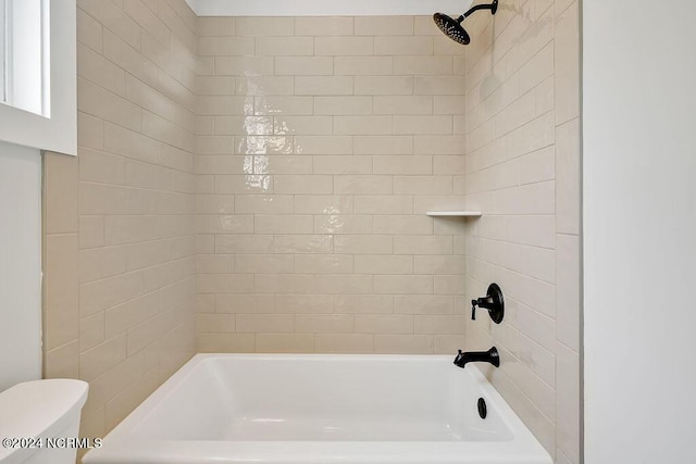 bathroom featuring toilet and tiled shower / bath