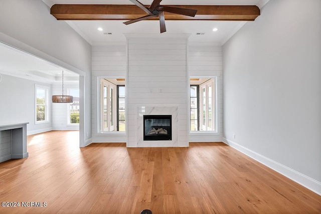 unfurnished living room featuring light wood-type flooring, a wealth of natural light, a high end fireplace, and ceiling fan