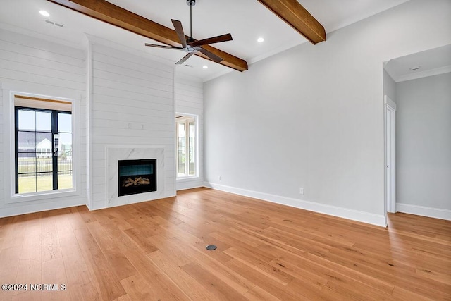 unfurnished living room with light wood-type flooring, ceiling fan, a fireplace, and beamed ceiling