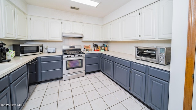 kitchen featuring white cabinetry, light tile patterned floors, blue cabinetry, and appliances with stainless steel finishes