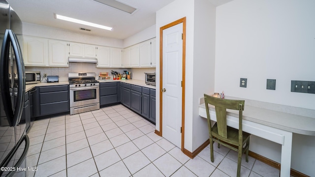 kitchen featuring gray cabinets, white cabinets, decorative backsplash, light tile patterned floors, and stainless steel appliances