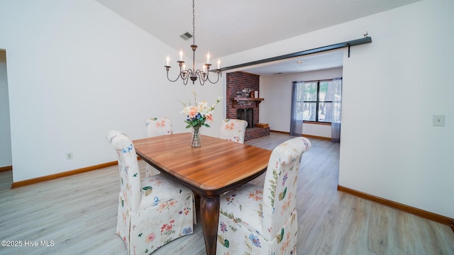 3 Bayberry Cir, Carolina Shores, NC 28467 - dining room with a chandelier, light wood-type flooring, a brick fireplace, and lofted ceiling
