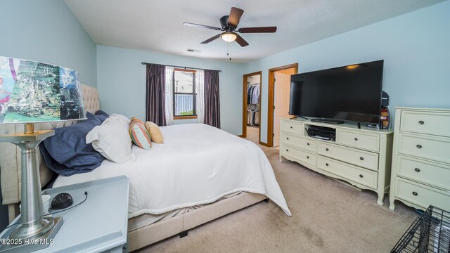 carpeted bedroom featuring a spacious closet, a textured ceiling, ceiling fan, and a closet