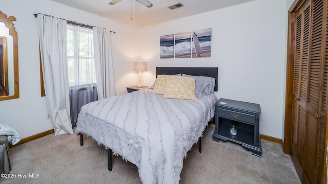 bedroom with light colored carpet, ceiling fan, and a closet