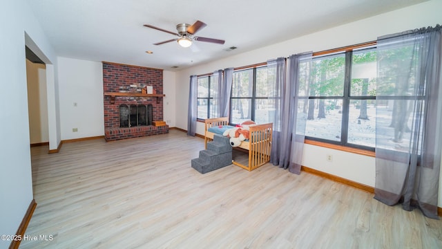 unfurnished living room featuring ceiling fan, a fireplace, light wood-type flooring, and a wealth of natural light