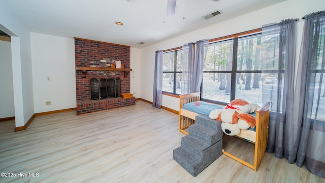 living room featuring a brick fireplace, hardwood / wood-style floors, and ceiling fan