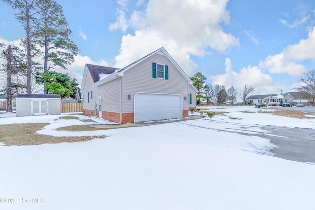 view of snow covered exterior featuring a garage and a storage shed