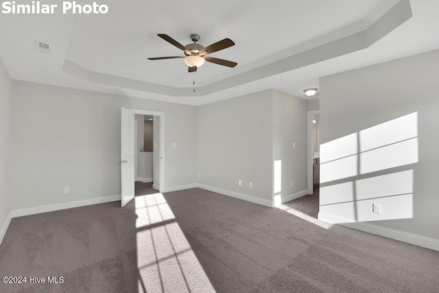 unfurnished room with crown molding, dark carpet, a raised ceiling, and ceiling fan