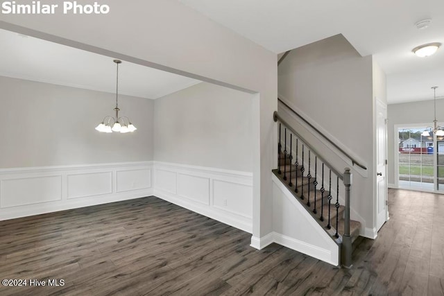 stairs with wood-type flooring and an inviting chandelier