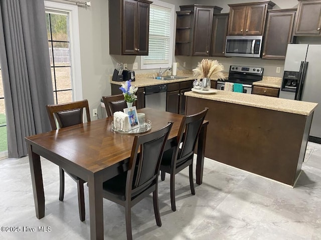 kitchen featuring dark brown cabinets, a kitchen island, appliances with stainless steel finishes, and sink