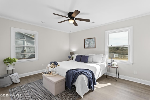 bedroom with baseboards, visible vents, wood finished floors, and ornamental molding