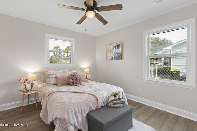 bedroom with ornamental molding, visible vents, baseboards, and wood finished floors