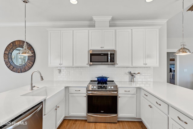 kitchen with stainless steel appliances, white cabinetry, and pendant lighting