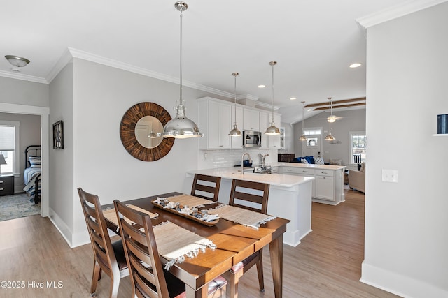 dining room with ceiling fan, ornamental molding, and light wood-type flooring