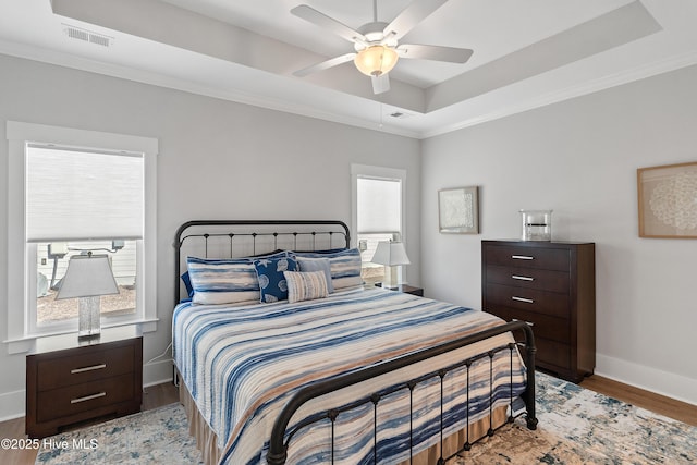 bedroom featuring a raised ceiling, ornamental molding, ceiling fan, and light hardwood / wood-style floors