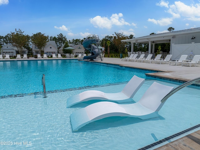 view of swimming pool featuring a water slide and a patio area