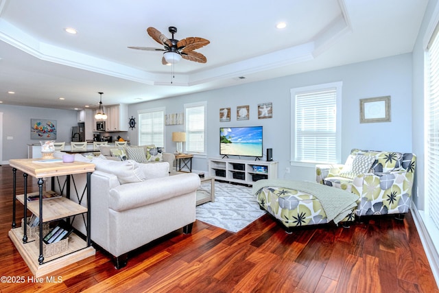 living room with dark hardwood / wood-style floors, a raised ceiling, and ceiling fan