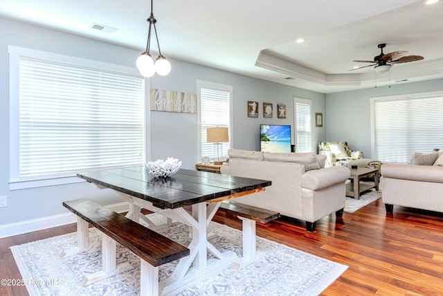 dining room with hardwood / wood-style flooring, ceiling fan, and a tray ceiling