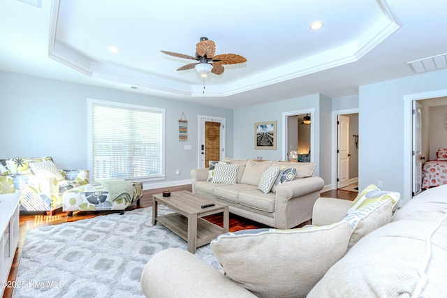 living room featuring a tray ceiling, light hardwood / wood-style flooring, and ceiling fan