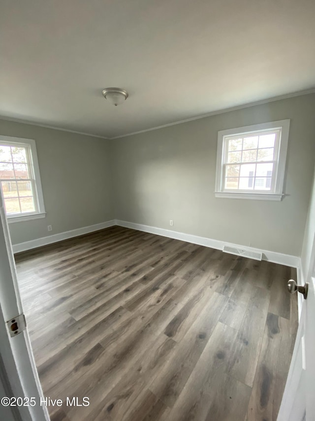 spare room featuring dark wood-type flooring and ornamental molding