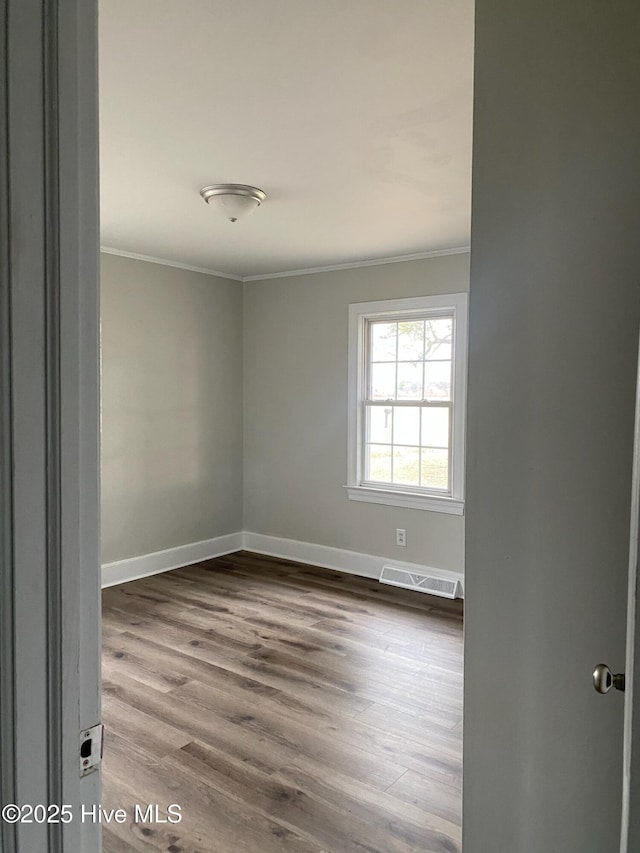 spare room featuring wood-type flooring and crown molding