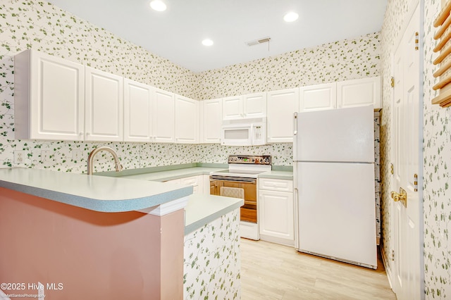 kitchen with white cabinetry, sink, white appliances, and kitchen peninsula