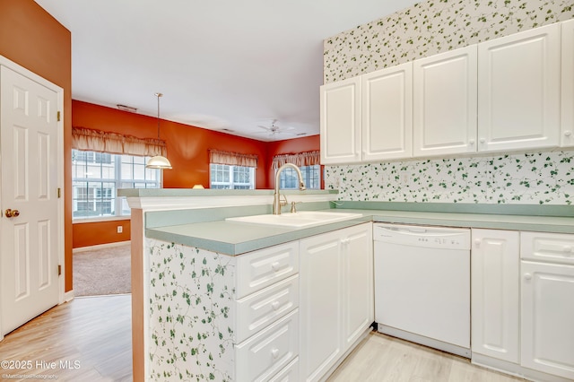 kitchen featuring white dishwasher, white cabinets, kitchen peninsula, and hanging light fixtures