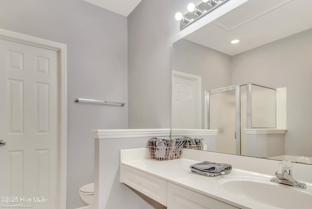 bathroom with toilet, vanity, and a shower with door