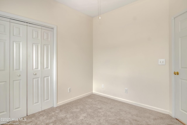 unfurnished bedroom with light colored carpet and a closet