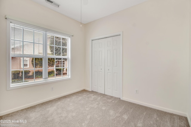 unfurnished bedroom with light carpet, a closet, and multiple windows