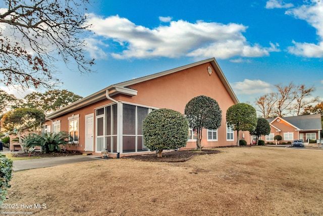 view of side of property with a yard and a sunroom