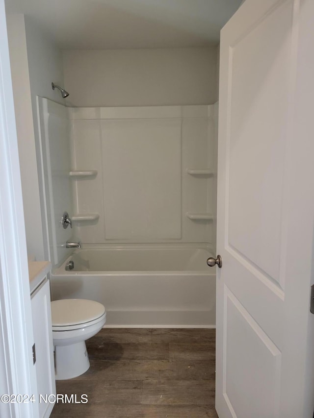 full bathroom with toilet, hardwood / wood-style floors, vanity, and washtub / shower combination