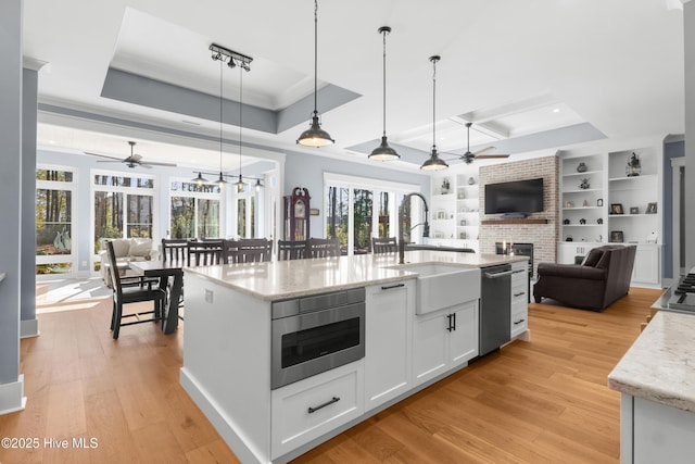 kitchen with built in shelves, hanging light fixtures, a raised ceiling, stainless steel appliances, and white cabinets