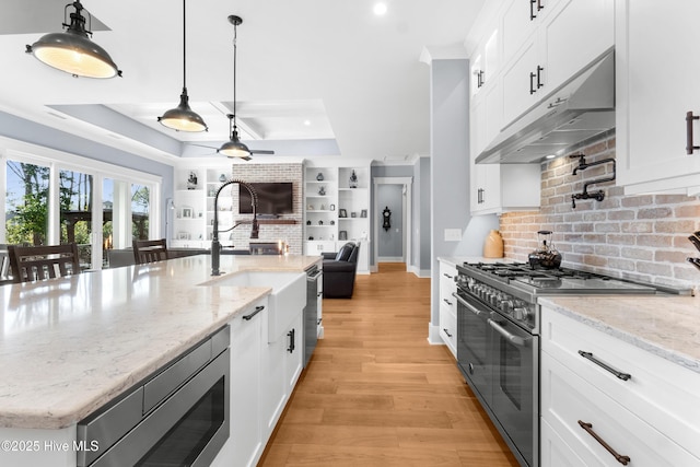 kitchen with light stone counters, hanging light fixtures, a raised ceiling, stainless steel appliances, and white cabinets