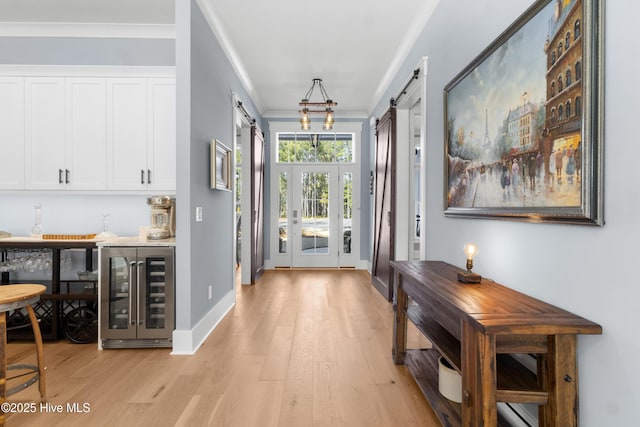 entryway with crown molding, a barn door, wine cooler, and light hardwood / wood-style flooring