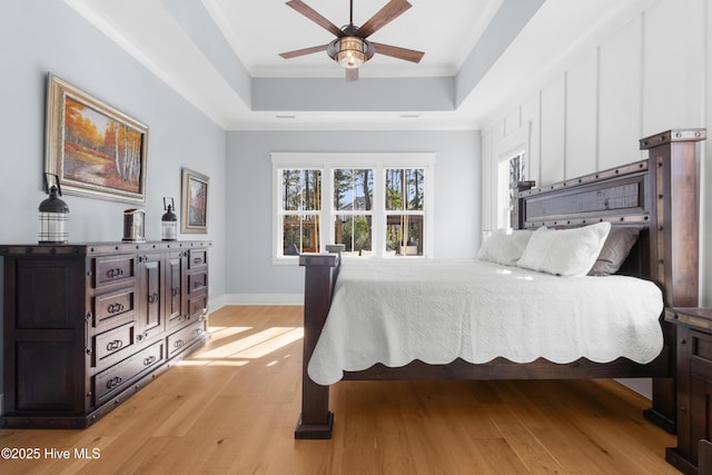 bedroom featuring ceiling fan, a raised ceiling, and light wood-type flooring