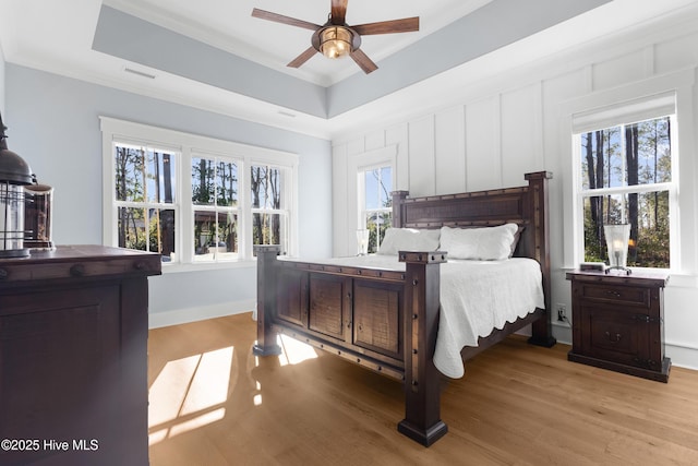 bedroom with a raised ceiling, crown molding, ceiling fan, and light hardwood / wood-style floors